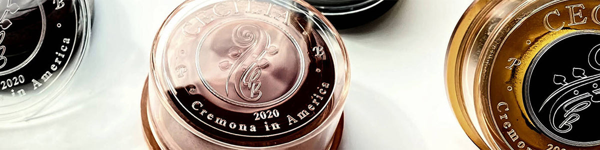 Close-up banner featuring Cecilia Rosin products with embossed Cecilia logos and Cremona in America branding on transparent rosin cases.