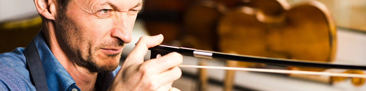 Skilled German bow maker carefully inspecting a Müsing carbon fiber bow during the craftsmanship and quality control process