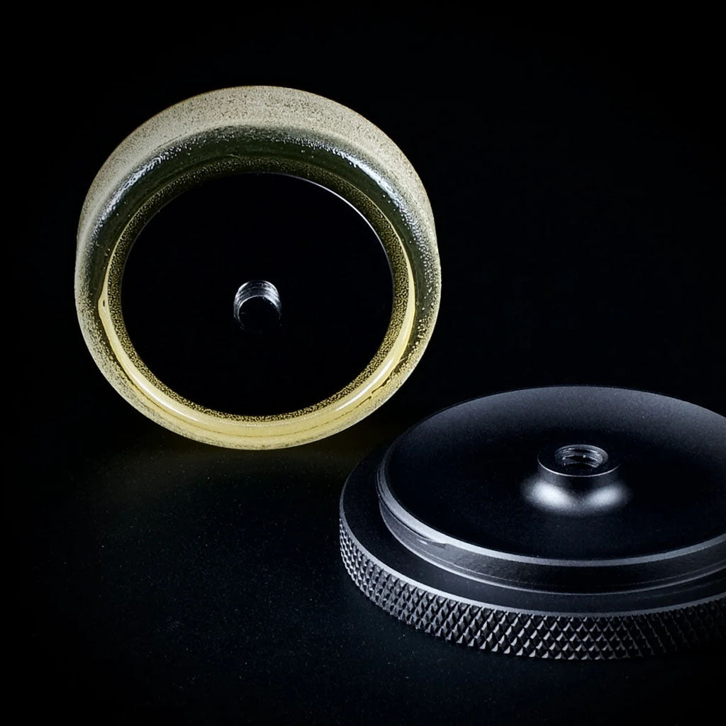 Cecilia Artist Reserve Divinum Rosin shown from underneath with its detachable black metal holder and threaded mounting mechanism against a black background.