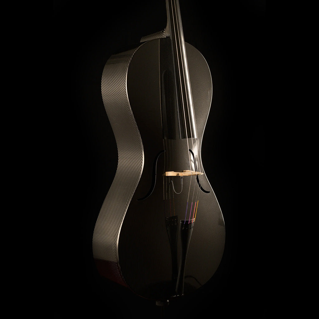 Three-quarter view of a Mezzo-Forte carbon fiber cello from the left, with light reflecting off the glossy top and woven ribs, on a black background.